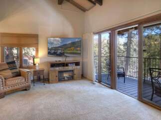 Experience mountain living in this charming living room featuring a cozy leather armchair and a modern entertainment center with a fireplace.