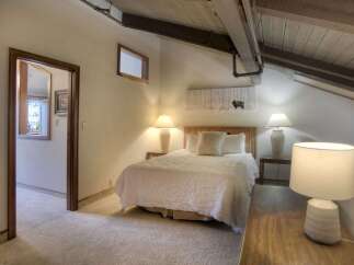 Discover this charming bedroom featuring a cozy queen-size bed adorned with a textured white quilt and plush pillows.