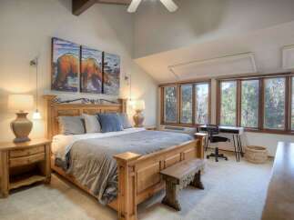Experience rustic charm in this spacious bedroom, featuring a grand wooden bed and a stunning triptych artwork of bears.