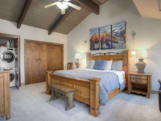 Experience rustic charm in this spacious bedroom featuring a grand wooden bed and a cozy seating bench.
