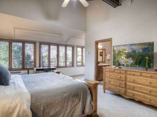 Experience serene living in this spacious bedroom, featuring a comfortable king-sized bed and large windows that offer picturesque views of the surrounding nature.