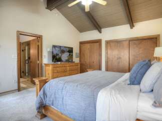 This charming bedroom features a vaulted ceiling with exposed wooden beams and a ceiling fan for optimal comfort.