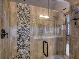 Experience luxury in this stunning bathroom featuring a spacious walk-in shower with elegant pebble tile accents.