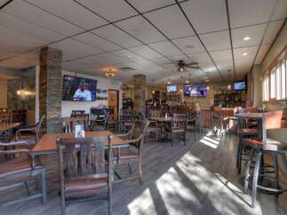 Experience the vibrant atmosphere of this restaurant and bar, featuring a well-stocked bar, ample seating with comfortable chairs and booths, and multiple televisions for entertainment.