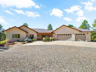 Discover this stunning stucco home featuring a welcoming covered entryway with exposed wood beams, leading to a spacious interior.