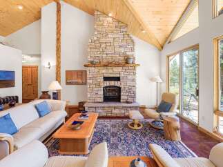 Experience rustic charm in this spacious living room, featuring a grand stone fireplace as the centerpiece.