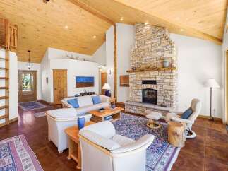 Experience rustic charm in this spacious living room, featuring a grand stone fireplace as the centerpiece.