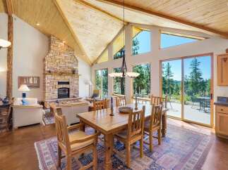 Experience breathtaking mountain views from this stunning home featuring a grand stone fireplace and vaulted wood-beamed ceilings.
