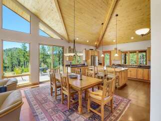Experience breathtaking mountain views from this stunning open-concept living space, featuring a vaulted wood-paneled ceiling and expansive windows that flood the area with natural light.
