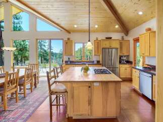 Experience breathtaking natural beauty from this stunning kitchen and dining area, featuring expansive windows and a vaulted wood-paneled ceiling.