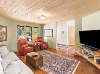 Experience rustic charm in this inviting living room, featuring a warm wood-paneled ceiling and comfortable seating.