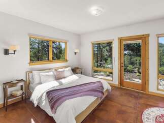Experience serene living in this charming bedroom, featuring a comfortable queen-size bed adorned with crisp white linens and a cozy purple throw.