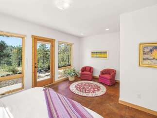 Experience serene living with abundant natural light streaming through large windows, offering picturesque views of the surrounding forest.