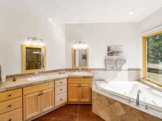 Indulge in luxury in this spacious master bathroom, featuring dual vanities with ample counter space and custom wood cabinetry.