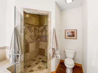 Experience luxury in this stunning bathroom featuring a spacious walk-in shower with intricate tile work and a glass enclosure.