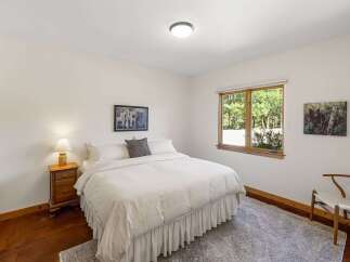This charming bedroom features a comfortable queen-size bed with crisp white linens and a decorative throw pillow.