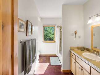 This charming bathroom features a spacious vanity with a tiled countertop and ample storage, perfect for organizing your essentials.