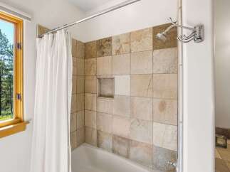 Experience tranquility in this charming bathroom featuring a bathtub and shower combo, accented by natural stone tiles.