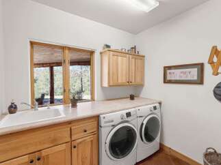 This spacious laundry room features a large white sink, ample counter space, and matching GE washer and dryer units.