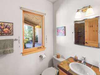This charming bathroom features a unique tiled vanity with a vessel sink, complemented by a rustic wooden medicine cabinet.
