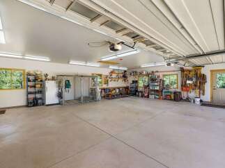 This spacious garage offers ample storage solutions, including shelving units, a refrigerator, and a large dog kennel.
