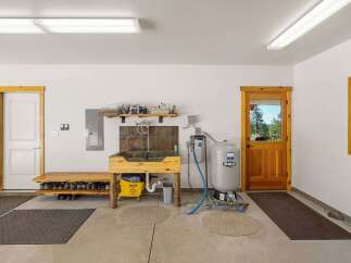 This spacious garage features a large utility sink with a tiled backsplash, perfect for cleaning and various projects.