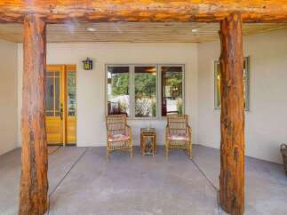 Welcome guests to this charming home with a rustic-inspired covered porch, featuring natural wood beams and sturdy log pillars.