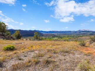 Discover breathtaking panoramic views from this expansive property, showcasing rolling hills, distant mountains, and a vibrant valley below.