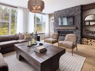 Experience luxury mountain living in this stunning living room, featuring a floor-to-ceiling stone fireplace and a large sectional sofa perfect for cozy evenings.