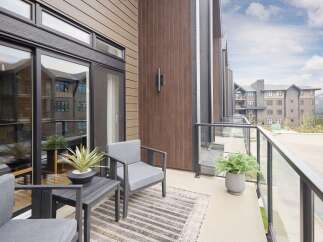 Enjoy outdoor living on this spacious balcony featuring comfortable seating and lush greenery.