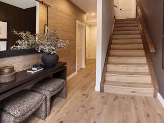 Step into this inviting entryway featuring a textured grasscloth wallpaper accent wall and a sleek dark wood console table.