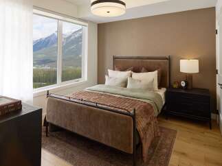 Experience serene mountain living in this beautifully appointed bedroom, featuring a plush velvet bed and a stunning panoramic window showcasing breathtaking alpine views.