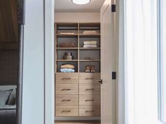 Step into a beautifully organized walk-in closet featuring custom wood cabinetry with ample drawer and shelf space.