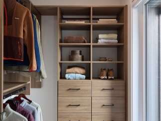 Discover organized living in this spacious walk-in closet, featuring custom wood cabinetry and ample hanging space.