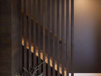 Experience modern elegance with this stunning staircase featuring a dark wood slatted screen, creating a sophisticated and private entryway.