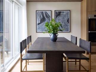 This dining room features a dark wood table with a textured base, complemented by minimalist leather chairs with wooden frames.