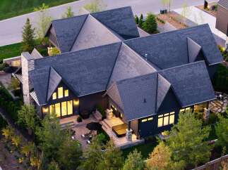 Experience luxury living in this stunning modern home, featuring a striking dark exterior and multiple gabled roofs.