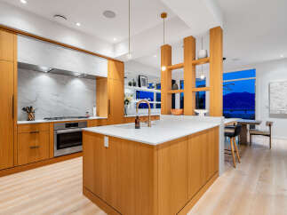 Experience modern luxury in this stunning kitchen, featuring sleek wood cabinetry and a striking marble backsplash.