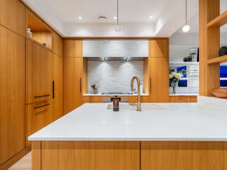 Experience modern luxury in this stunning kitchen, featuring sleek, custom wood cabinetry and a pristine white quartz island.