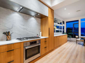 Experience modern luxury in this stunning kitchen featuring sleek wood cabinetry and a sophisticated marble backsplash.