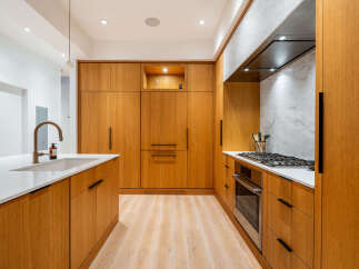 Experience modern luxury in this stunning kitchen, featuring sleek, warm wood cabinetry that seamlessly integrates high-end appliances.