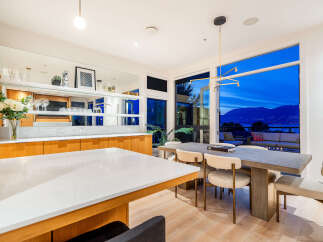Experience luxurious living with this stunning dining and bar area, featuring a sleek white island and elegant wooden cabinetry.
