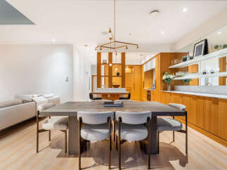 Experience modern living in this beautifully appointed dining and kitchen area, featuring a sleek wooden dining table with comfortable upholstered chairs.