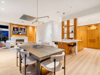 Experience modern luxury in this open-concept living space, featuring a sleek dining area with a large wooden table and comfortable upholstered chairs.