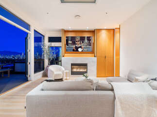 Experience luxury living with this stunning modern living room, featuring a cozy fireplace and a large television for entertainment.
