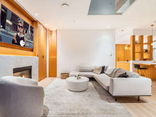 Experience modern luxury in this stunning living space, featuring a sleek fireplace and a large television mounted above.