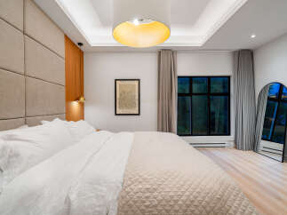 Experience modern luxury in this serene bedroom, featuring a plush, upholstered headboard and crisp white linens for ultimate comfort.