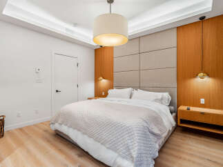 Experience modern luxury in this master bedroom, featuring a king-sized bed with crisp white linens and a plush quilted throw.
