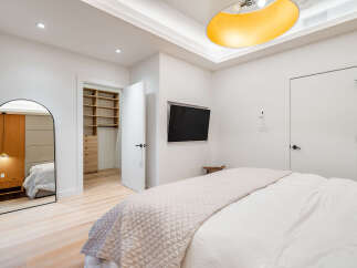 Step into this modern bedroom featuring a spacious walk-in closet with ample shelving and drawers.