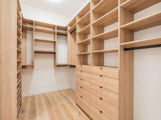 Step into this spacious walk-in closet, featuring custom light wood shelving and ample storage solutions.
